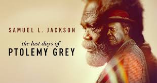 "A promotional still from the 2022 drama The Last Days of Ptolemy Grey shows actor Samuel L. Jackson as Ptolemy Grey, an elderly man with dementia, sitting pensively in a cluttered apartment. His expression reflects confusion and resilience, with warm lighting highlighting the emotional tone of the series. The background features aged books and memorabilia, emphasizing themes of memory and legacy."