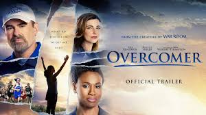 "Inspirational Overcomer poster featuring coach John Harrison (Alex Kendrick) kneeling beside young runner Hannah Scott (Aryn Wright-Thompson) on a track at sunset. Hannah wears a cross-country uniform while catching her breath, as the coach offers encouraging words. Golden light filters through trees in the background with the tagline 'What do you allow to define you?'"