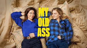 "Whimsical poster for My Old Ass showing young Elliott (Maisy Stella) sitting cross-legged on a dock, staring in shock at her older self (Aubrey Plaza) who lounges beside her with amused confidence. A psychedelic sunset swirls across a lake behind them, blending their realities. The title appears in playful handwritten font with a doodled underline."