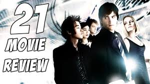 "A group of young MIT students, including Jim Sturgess and Kevin Spacey, stand around a blackjack table in a neon-lit Las Vegas casino, exchanging tense glances as chips pile up. The backdrop glows with slot machines and crowds, capturing the high-stakes thrill of their card-counting scheme."